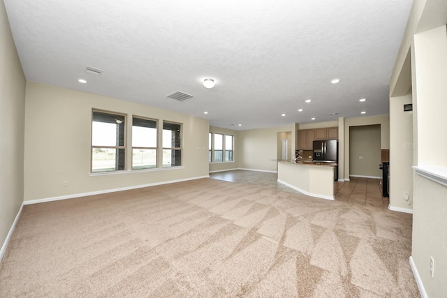 unfurnished living room featuring light carpet and a textured ceiling