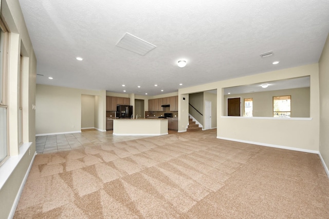 unfurnished living room with light colored carpet and a textured ceiling