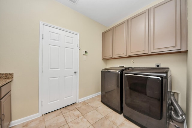 laundry area featuring washer and dryer, cabinets, and light tile patterned flooring