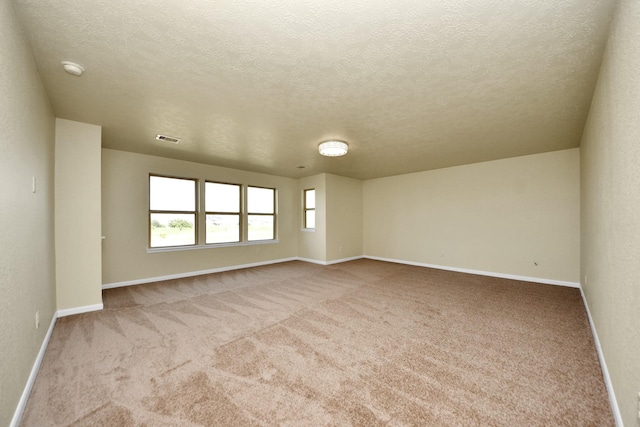 empty room featuring light colored carpet and a textured ceiling