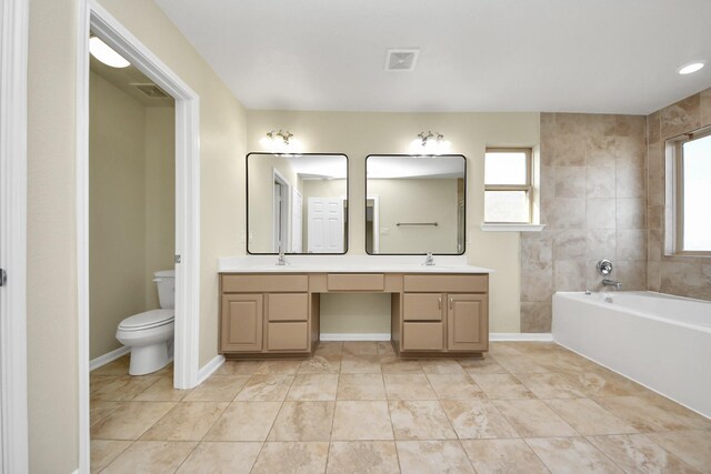 bathroom featuring toilet, vanity, a bath, and a wealth of natural light