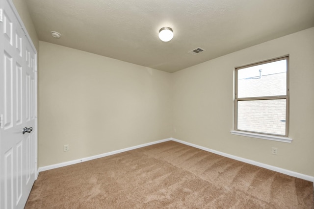 carpeted empty room with a textured ceiling