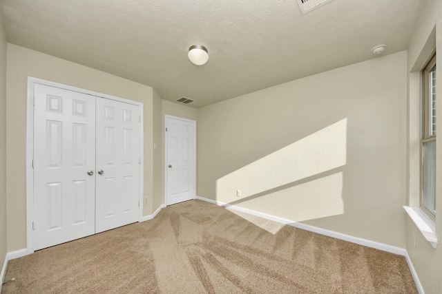 unfurnished bedroom with carpet floors, a closet, and a textured ceiling