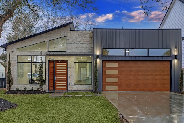 contemporary house featuring a garage and a lawn