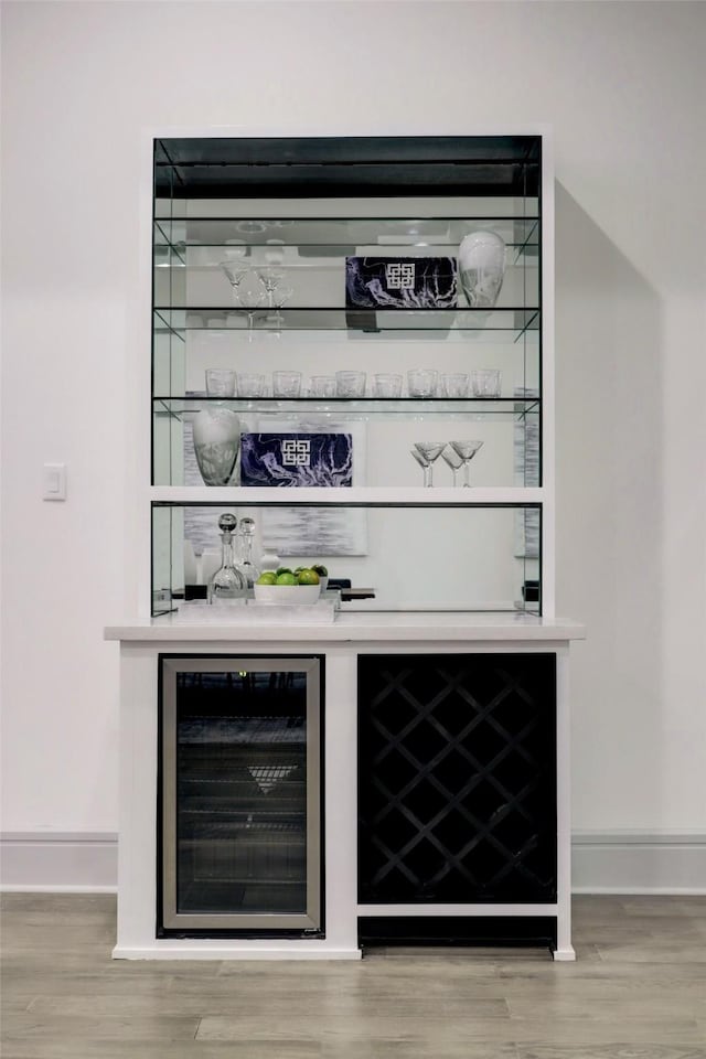 bar with wood-type flooring and beverage cooler