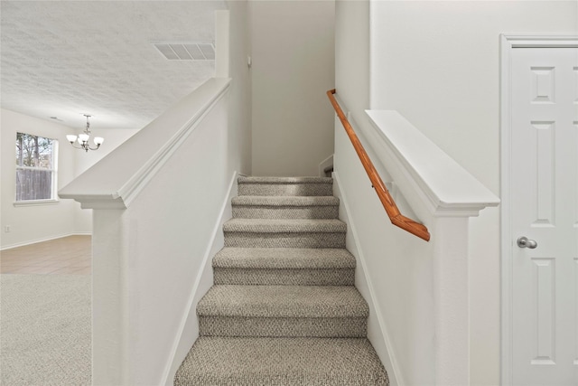 stairway featuring carpet floors, a chandelier, and a textured ceiling