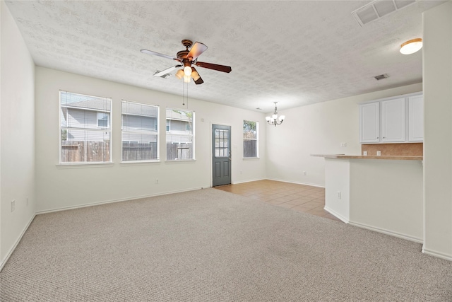 unfurnished living room featuring ceiling fan with notable chandelier, light carpet, and a textured ceiling