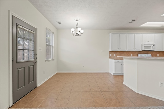 kitchen with white cabinetry, tasteful backsplash, a notable chandelier, a textured ceiling, and light tile patterned flooring