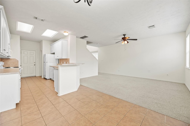 kitchen featuring range, light carpet, white refrigerator, kitchen peninsula, and white cabinets