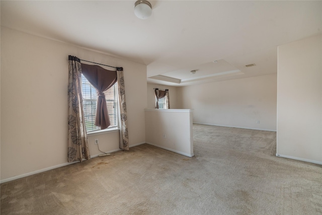 unfurnished room with a tray ceiling and light colored carpet