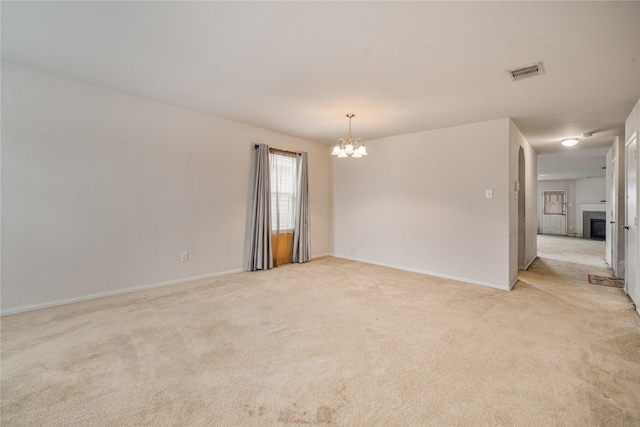 carpeted spare room featuring a chandelier and a tiled fireplace