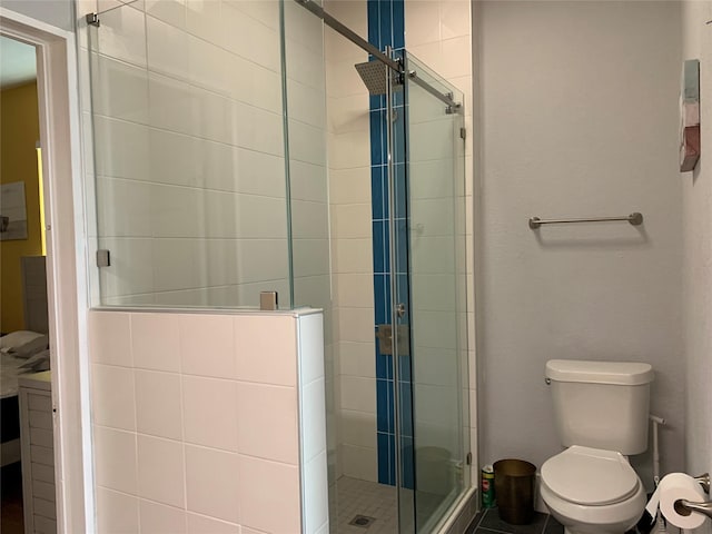 bathroom featuring a shower with shower door and toilet