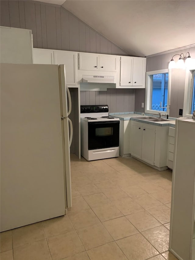 kitchen featuring vaulted ceiling, white cabinetry, white fridge, and electric range