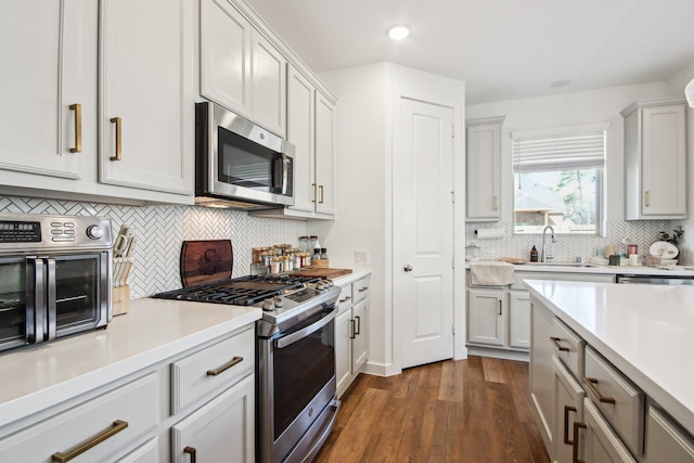 kitchen with sink, white cabinetry, tasteful backsplash, dark hardwood / wood-style flooring, and stainless steel appliances