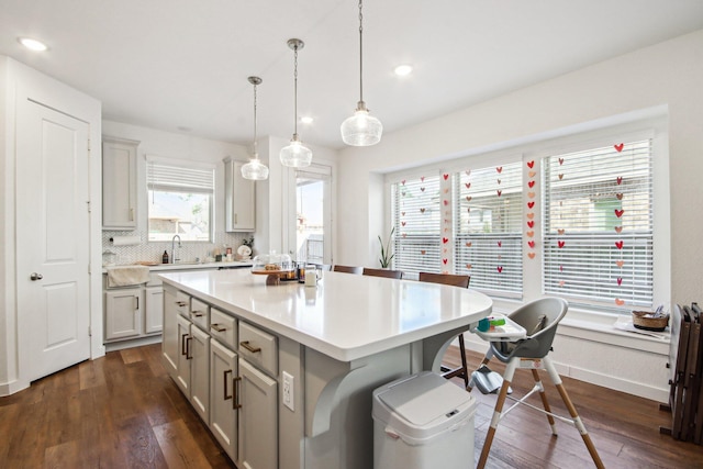 kitchen with pendant lighting, dark hardwood / wood-style floors, gray cabinetry, and a center island