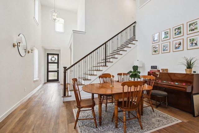 dining area with a chandelier, hardwood / wood-style floors, and a high ceiling