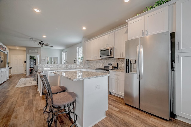 kitchen with white cabinetry, appliances with stainless steel finishes, a breakfast bar, and a center island