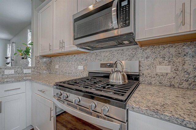 kitchen featuring white cabinetry, light stone counters, tasteful backsplash, and stainless steel appliances