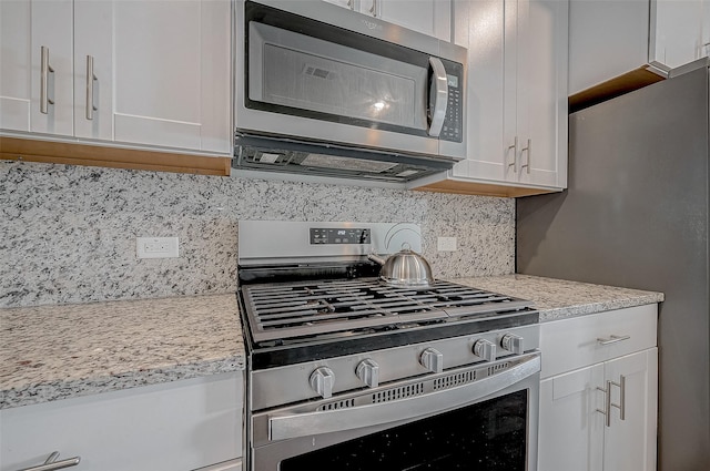 kitchen with stainless steel appliances, white cabinetry, and tasteful backsplash