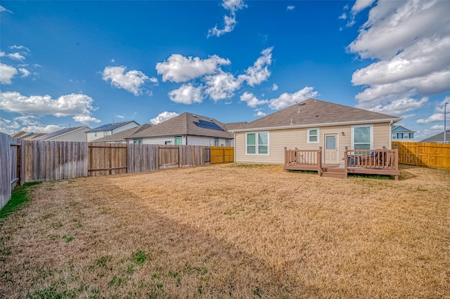 rear view of property featuring a wooden deck and a yard