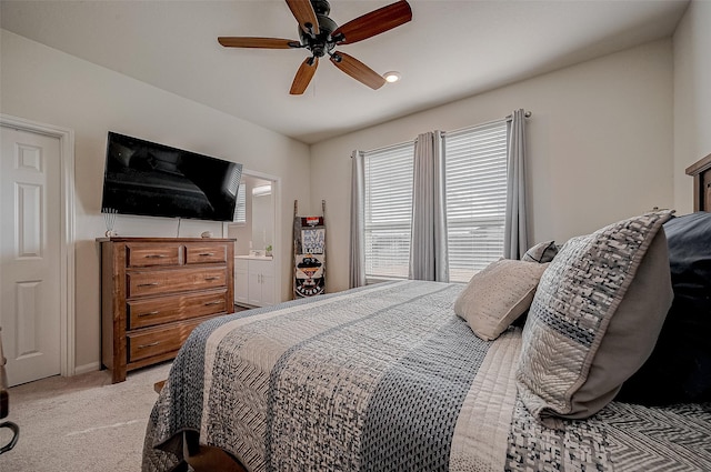 bedroom featuring ceiling fan, light colored carpet, and ensuite bathroom