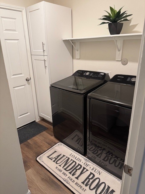 washroom featuring dark wood-type flooring, cabinets, and washing machine and clothes dryer