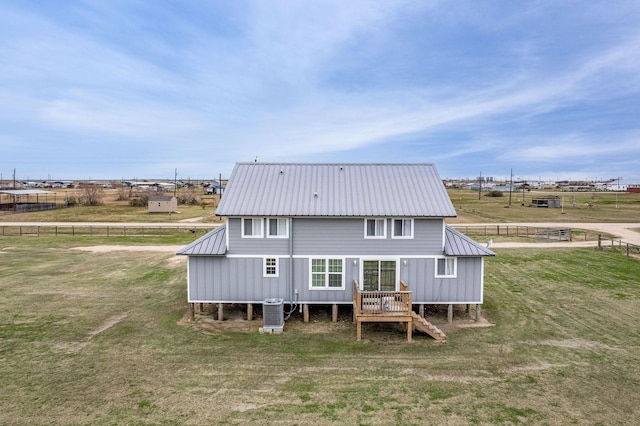 rear view of house with central AC and a lawn