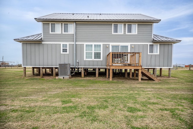 rear view of house with central AC, a deck, and a lawn