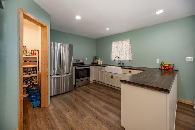 kitchen with sink, appliances with stainless steel finishes, white cabinets, dark hardwood / wood-style flooring, and kitchen peninsula