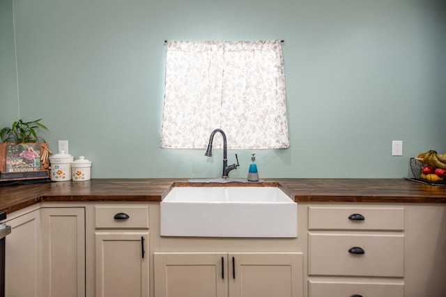 kitchen featuring butcher block counters, sink, and white cabinets