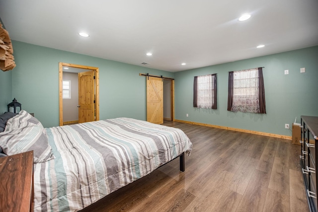 bedroom featuring wood-type flooring and a barn door