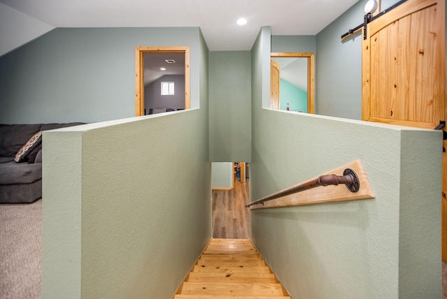 staircase with hardwood / wood-style flooring, vaulted ceiling, and a barn door