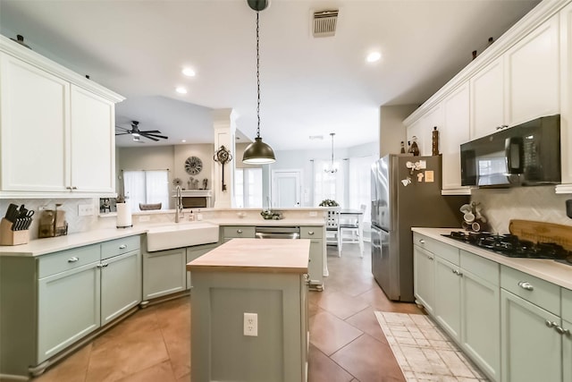 kitchen with pendant lighting, sink, black appliances, green cabinetry, and kitchen peninsula