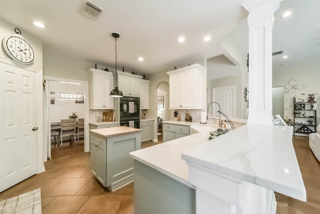 kitchen with decorative light fixtures, sink, white cabinets, kitchen peninsula, and tile patterned floors