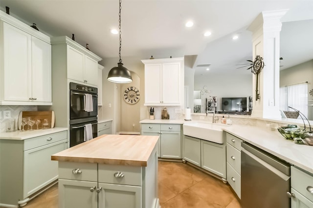 kitchen featuring sink, butcher block countertops, hanging light fixtures, stainless steel dishwasher, and double oven