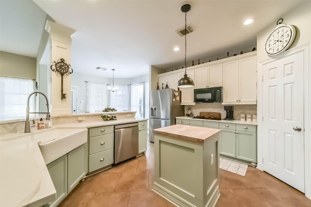 kitchen with decorative light fixtures, wooden counters, a center island, light tile patterned floors, and black appliances