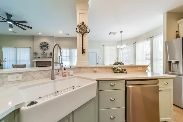 kitchen with sink, tasteful backsplash, pendant lighting, ceiling fan, and stainless steel appliances