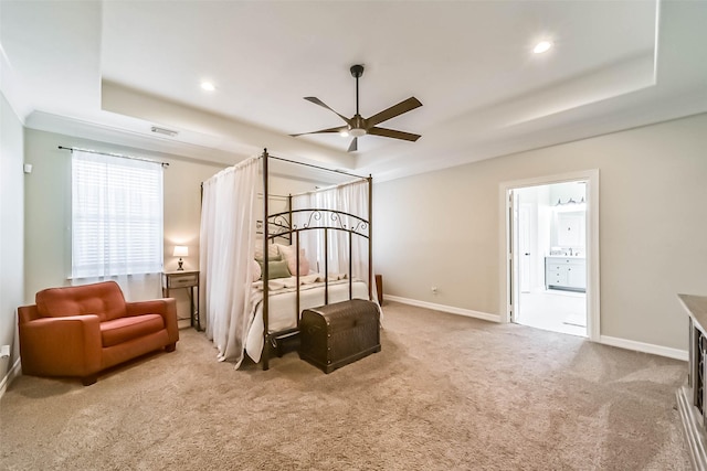 carpeted bedroom with ensuite bathroom and a tray ceiling