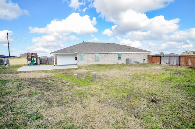 rear view of property featuring a playground, a patio area, and a lawn