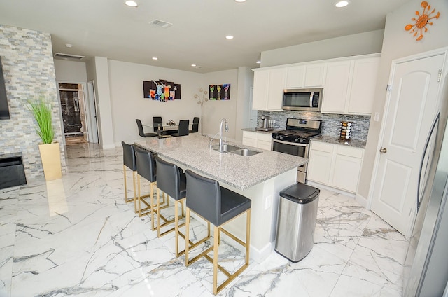 kitchen featuring stainless steel appliances, white cabinetry, and a kitchen island with sink