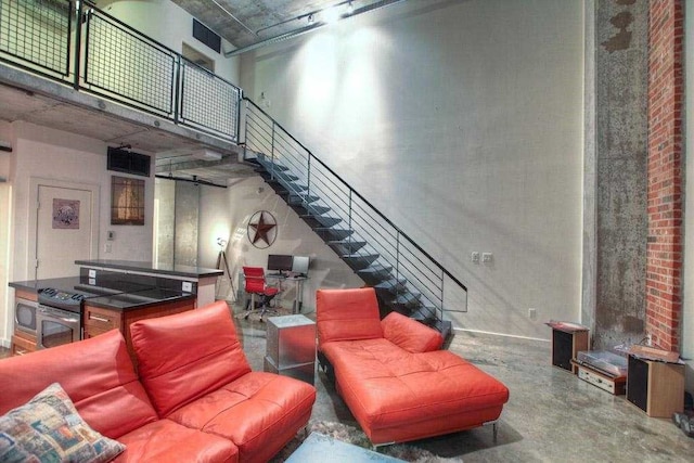 living room featuring concrete flooring and a towering ceiling