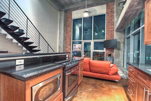 kitchen featuring brick wall, stainless steel appliances, hanging light fixtures, and a high ceiling