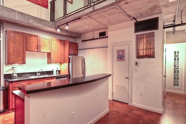 kitchen featuring rail lighting, a kitchen island, sink, and stainless steel fridge