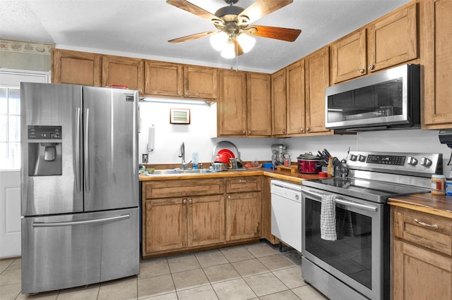 kitchen with light tile patterned flooring, appliances with stainless steel finishes, sink, and a textured ceiling