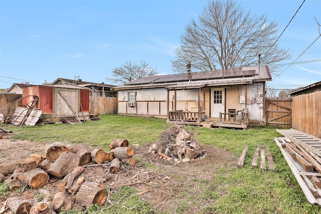 rear view of house with a wooden deck, a lawn, a shed, and solar panels