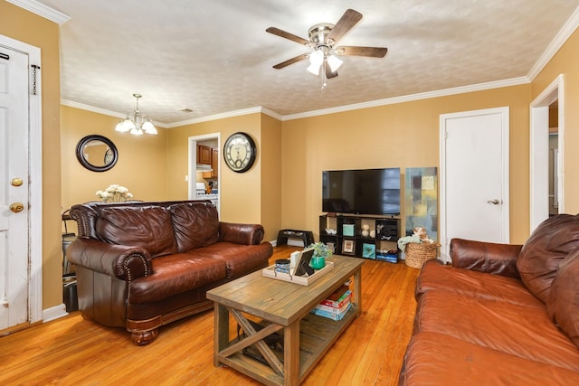 living room with ceiling fan with notable chandelier, ornamental molding, and light hardwood / wood-style floors