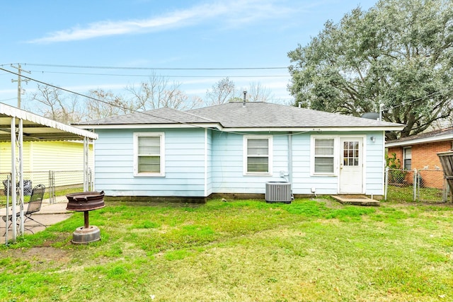 rear view of house with central AC, a yard, and a fire pit