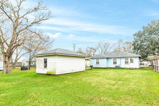 rear view of house with central AC, a lawn, and an outdoor structure