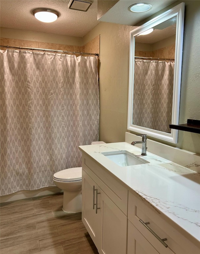 bathroom featuring vanity, a textured ceiling, and toilet