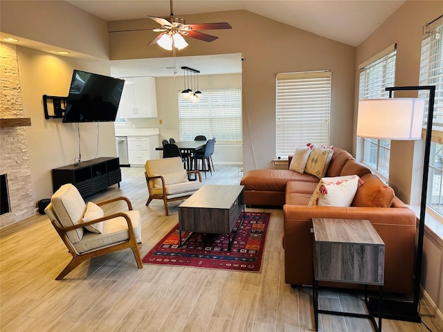 living room with a fireplace, light hardwood / wood-style floors, ceiling fan, and vaulted ceiling